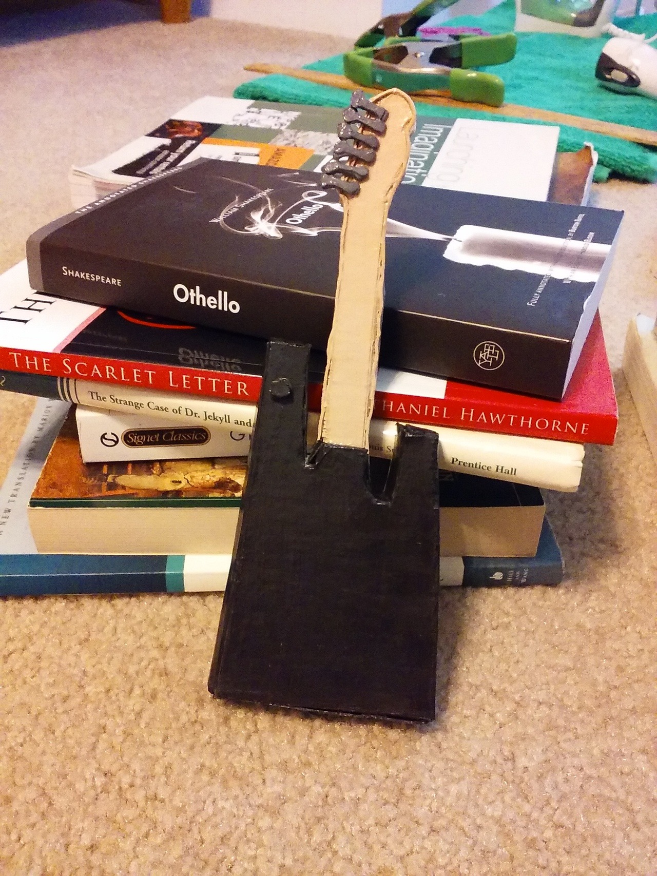 The back of the guitar leaning on a stack of books. The body is black and the neck is lighter brown.