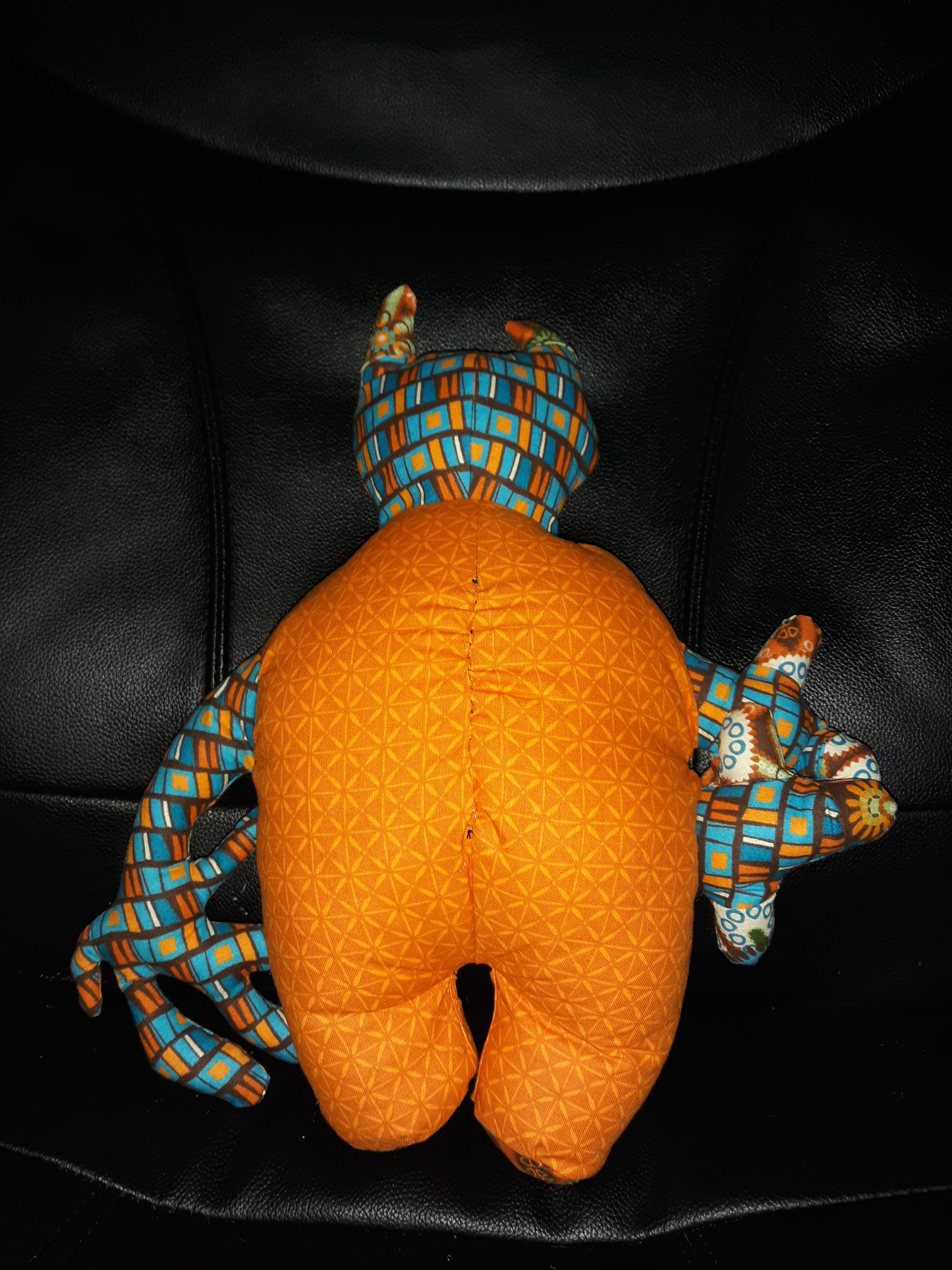 The back of the doll. The entirety of the back of the body is the same orange fabric. You can see that the fingers on the two short arms and the horns are of that brown floral pattern that the belly has.
