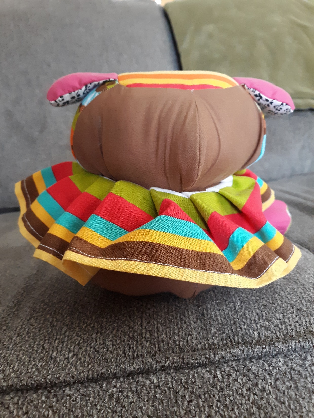 The back of the doll. You see that the top of the head and the bottom of the body has the same striped pattern has the neck ruffle. The doll has no arms.