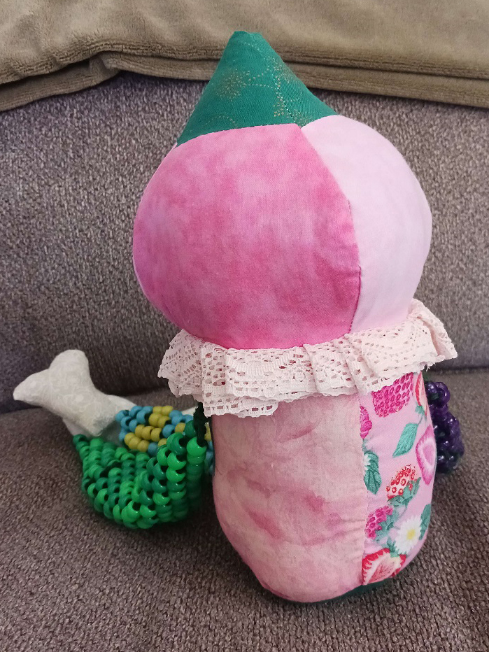 The back of the same doll. Looks similar to the front but there's no face and the limbs are mostly hidden behind it.