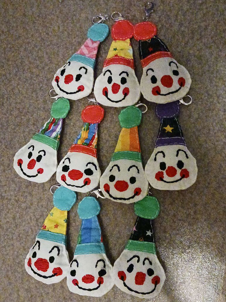 Keychains of various fabric clown faces wearing hats.