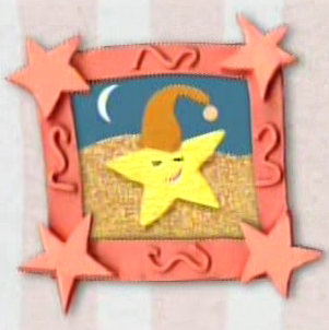 A pink square frame with stars in each corner hangs on the wall. The picture in the frame is of a yellow sea star wearing an orange cap on the beach. It is night time and the moon is out in the sky while the sea star sleeps.