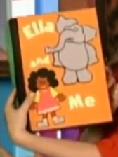 Marlee is holding a book that has the title 'Ella and Me' on it. The cover has an orange background with a picture of an elephant in the top right corner and a picture of a little girl in the bottom left corner.