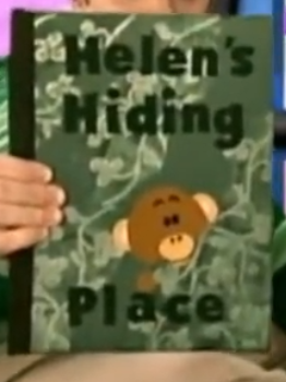 A picture of a book titled 'Helen's Hiding Place.' The cover is green with light green leaves on it. There's a monkey named Helen hiding behind some of the leaves.