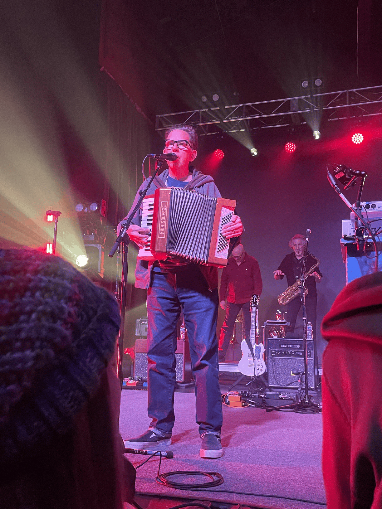 John Linnell on stage playing an accordion and singing into a microphone.