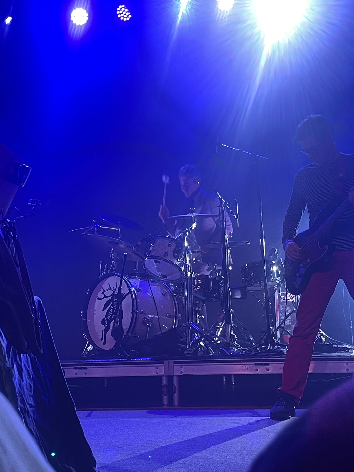 Marty Beller and Danny Weinkauf on stage. Beller is playing the drums whilst Weinkauf plays the bass guitar.