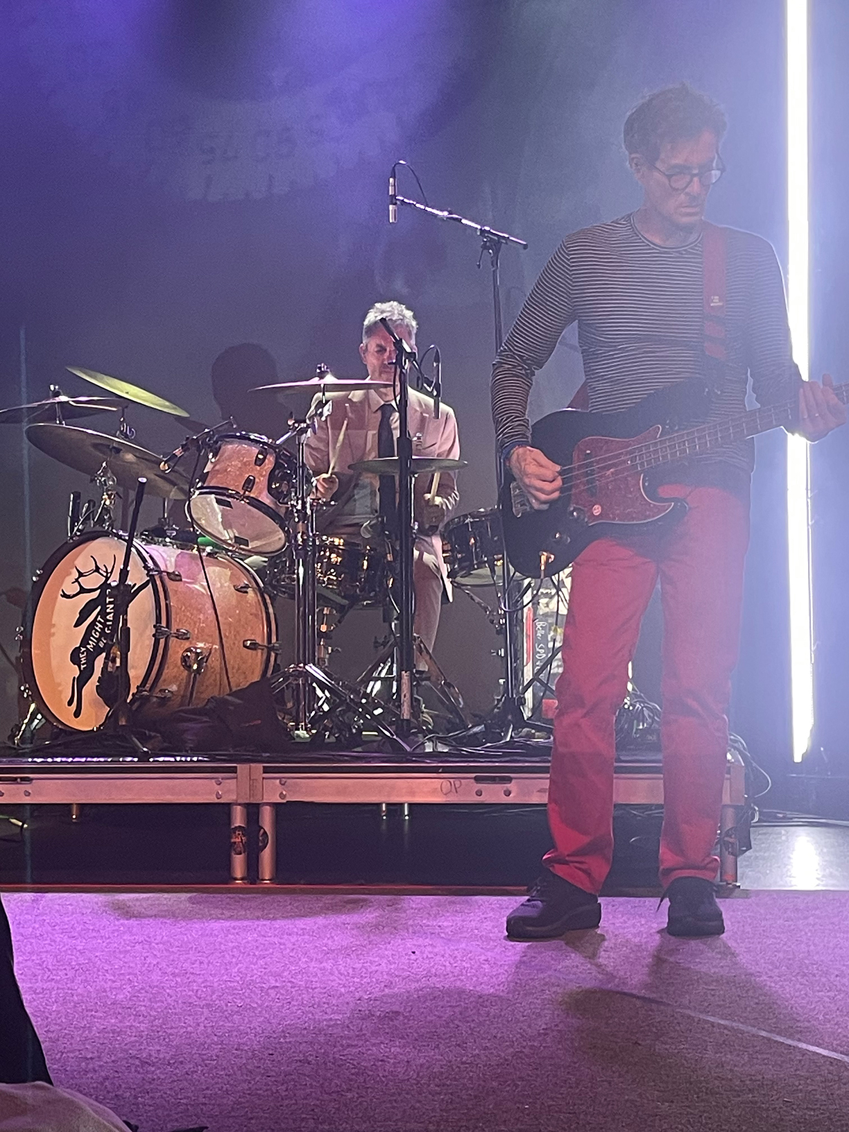 Marty Beller and Danny Weinkauf on stage. Beller is playing the drums whilst Weinkauf plays the bass guitar.