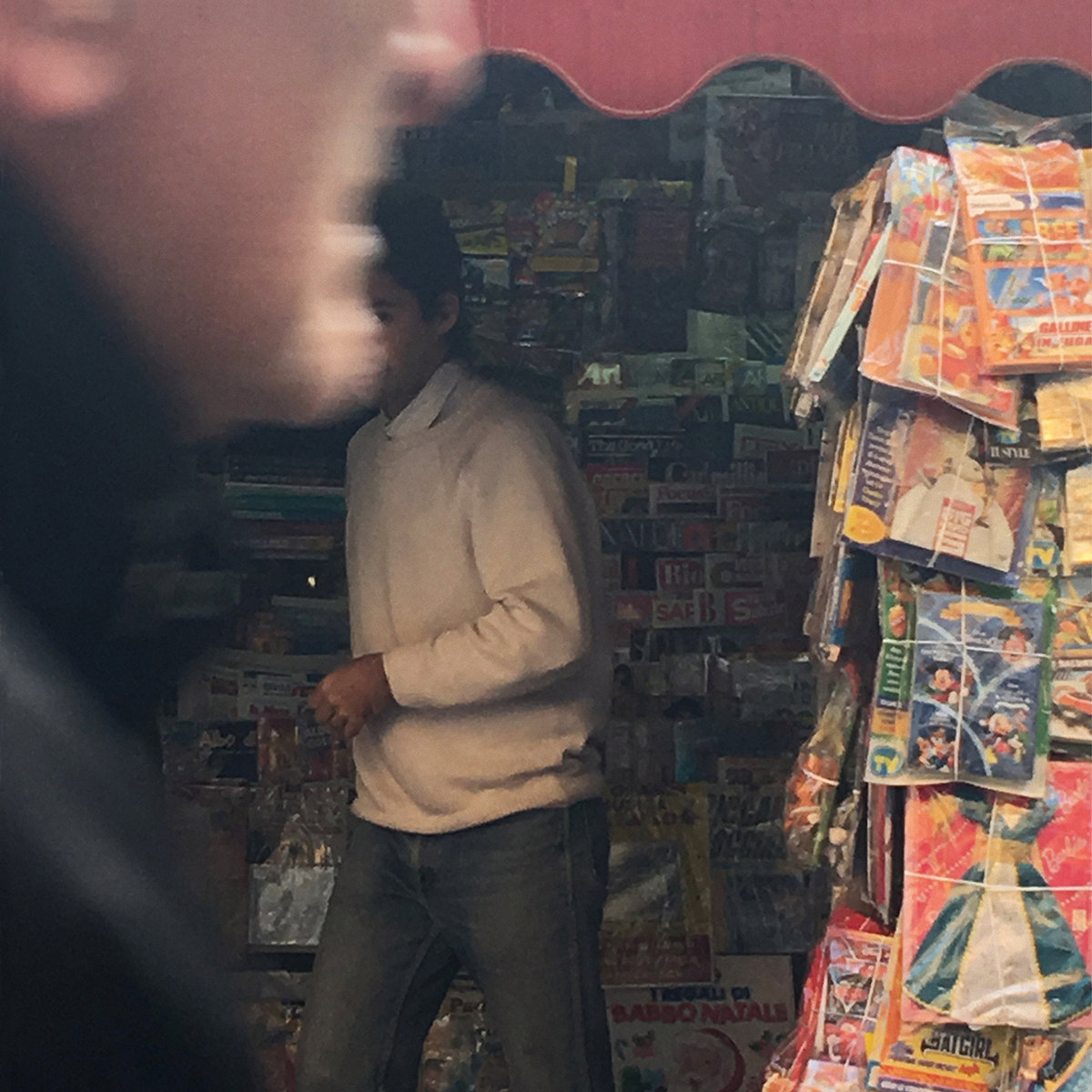 The cover of Introducing Juan Pablo by Juan Wauters. The cover is of Wauters within a magazine booth slightly obscured by a man within the foreground.