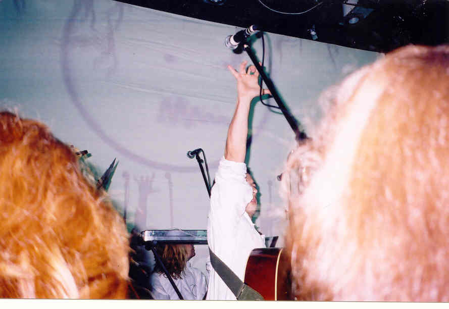Burns performing on stage. He has one arm stretched above himself.