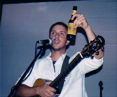 Burns on stage holding up a bottle of beer in one hand.