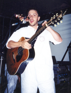 Burns on stage adjusting his guitar strap.