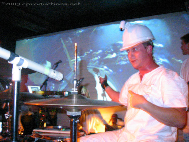 Jason wearing a helmet with a camera attached gesturing to the screen behind him.