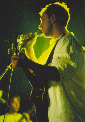 Burns singing into the microphone on stage.