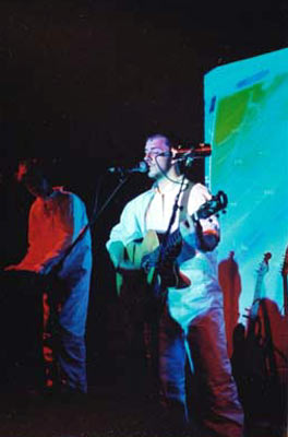 Burns performing on stage with an image projected behind him.