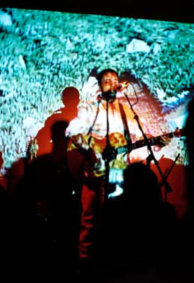 Burns performing on stage with an image projected behind him.
