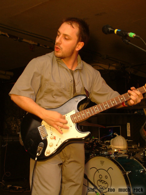 Burns playing electric guitar on stage.