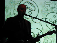 Burns singing whilst many dustmites are being projected on the screen behind him.