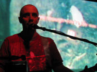 Burns performing whilst an image of Domo is being projected on his shirt and on the screen behind him.