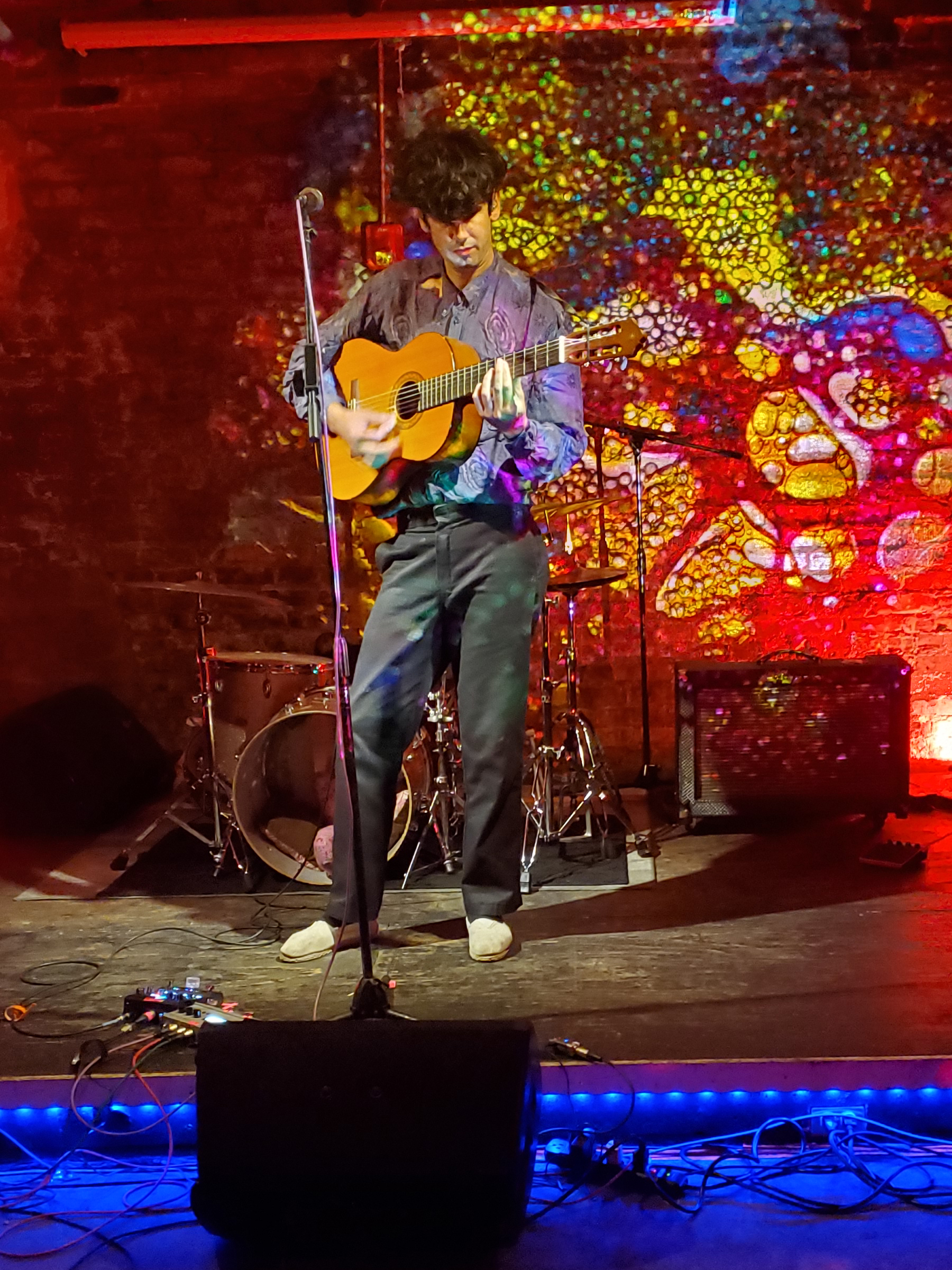 Tall Juan playing acoustic guitar on stage.