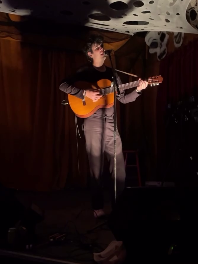 Tall Juan on stage playing acoustic guitar and singing into a microphone.