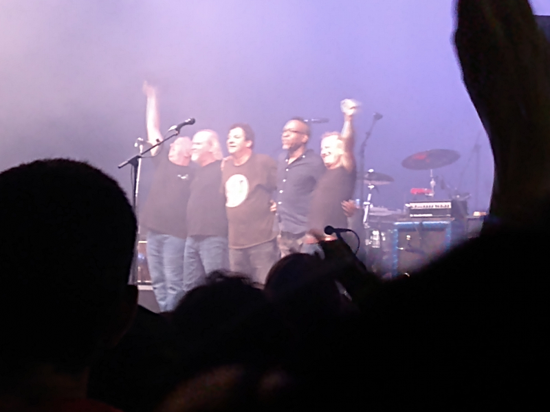 Ween on stage all standing in a line. From left to right: Gene Ween, Glenn McClelland, Dean Ween, Claude Coleman, and Dave Dreiwitz.