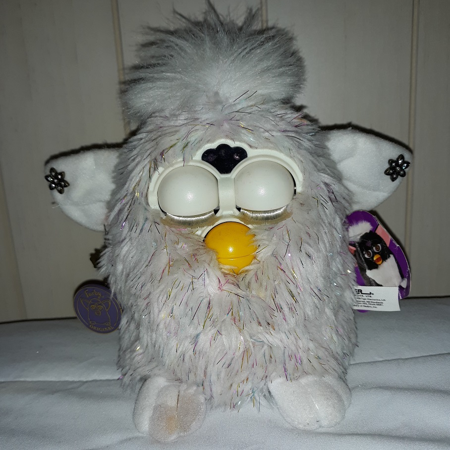 An all white furby with holographic streamers in the fur.
