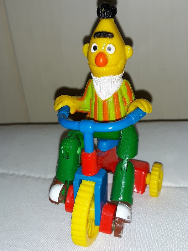 A plastic toy of Bert on a tricycle.