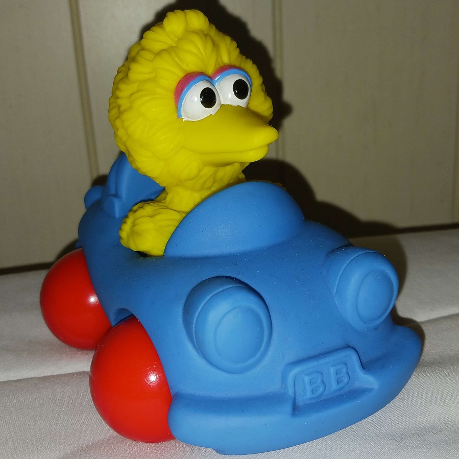 A plastic toy of Big Bird in a car.