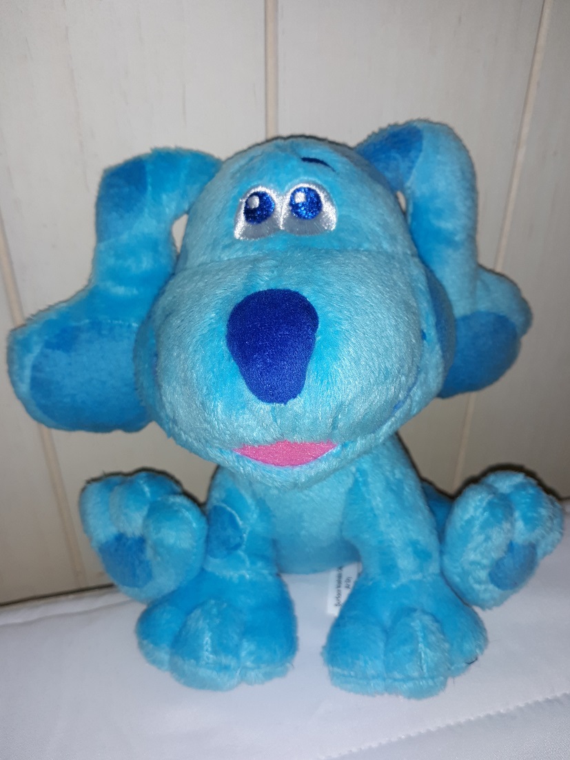 A plush doll of Blue that is sitting down. She has embroidered eyes with a fabric nose. Her mouth is open in a smile.