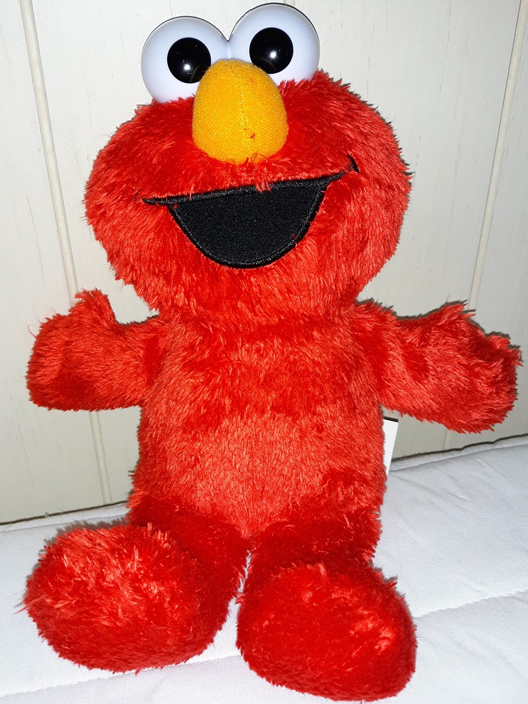 A plush doll of Elmo that has plastic eyes and a smile that is embroidered on.
