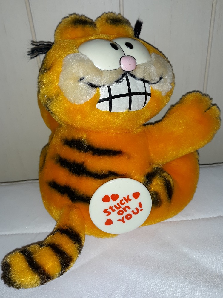 A plush doll of Garfield the cat. He has a big grin on his face. There is a button on his butt that says 'stuck on you!'