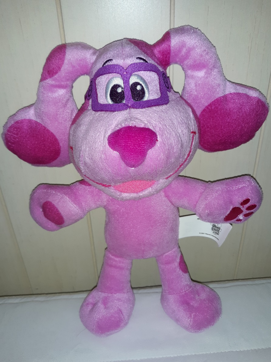 A plush doll of Magenta standing up. She has felt glasses on with embroidered eyes and a fabric nose. Her mouth is open in a smile.
