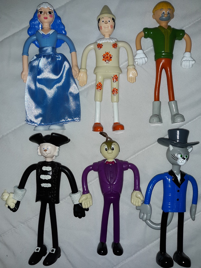 A group of plastic figurines from Benigni's adaptation of Pinocchio consisting of la Fata dai capelli turchini, Pinocchio, Geppetto, Medoro, il Grillo Parlante, and il Gatto.