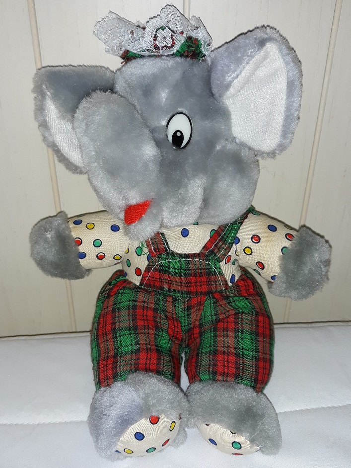 An elephant doll wearing a plaid hat with matching plaid overalls and a polka dot shirt underneath.